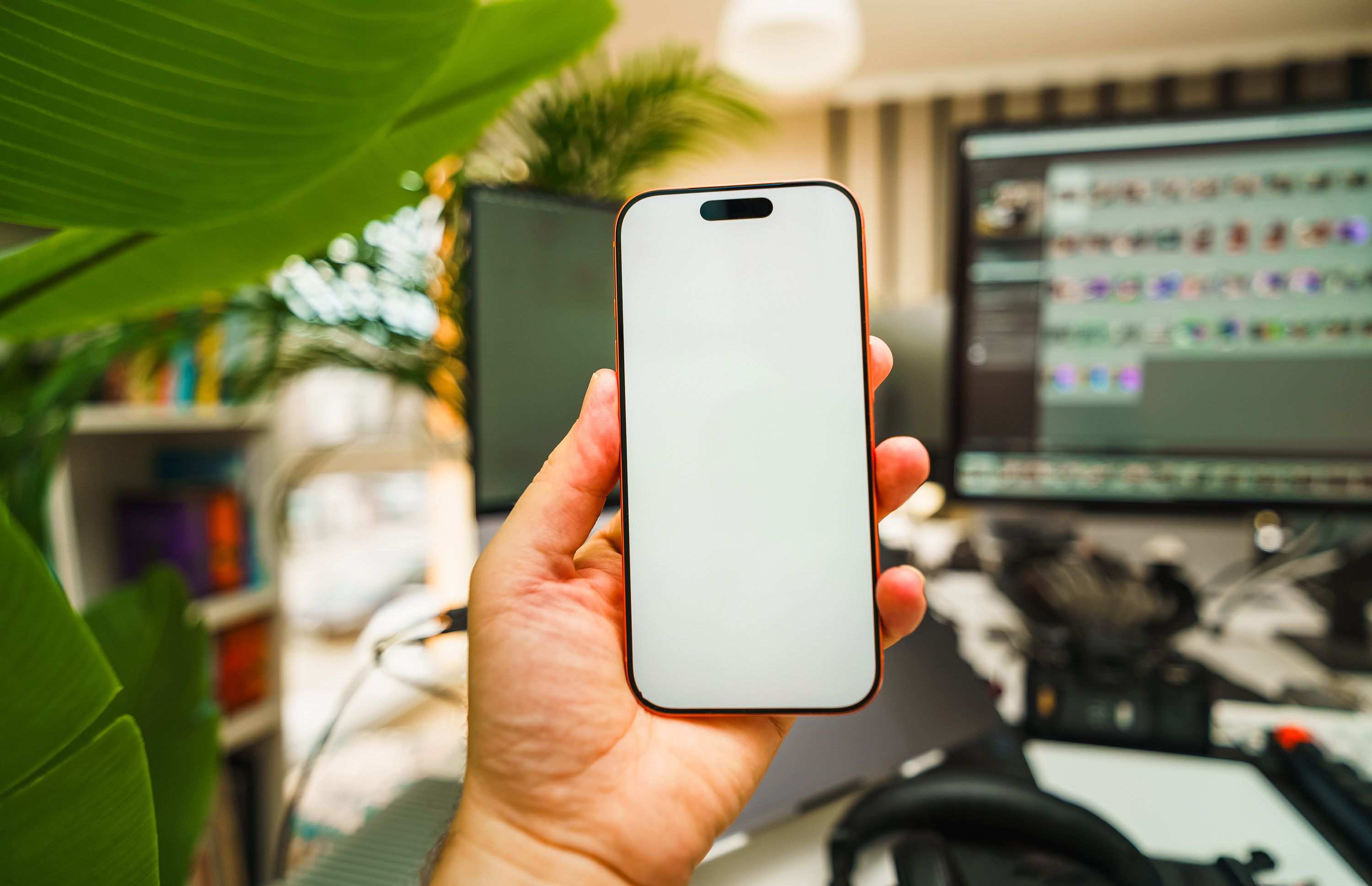 Hand hält Smartphone mit leerem Bildschirm im Büro
